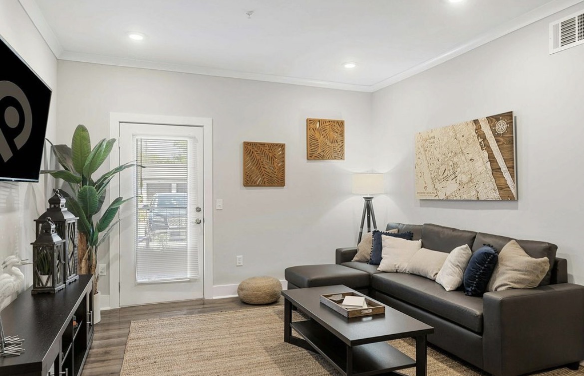 Living room with grey leather sofa, jute rug, wall art and patio door