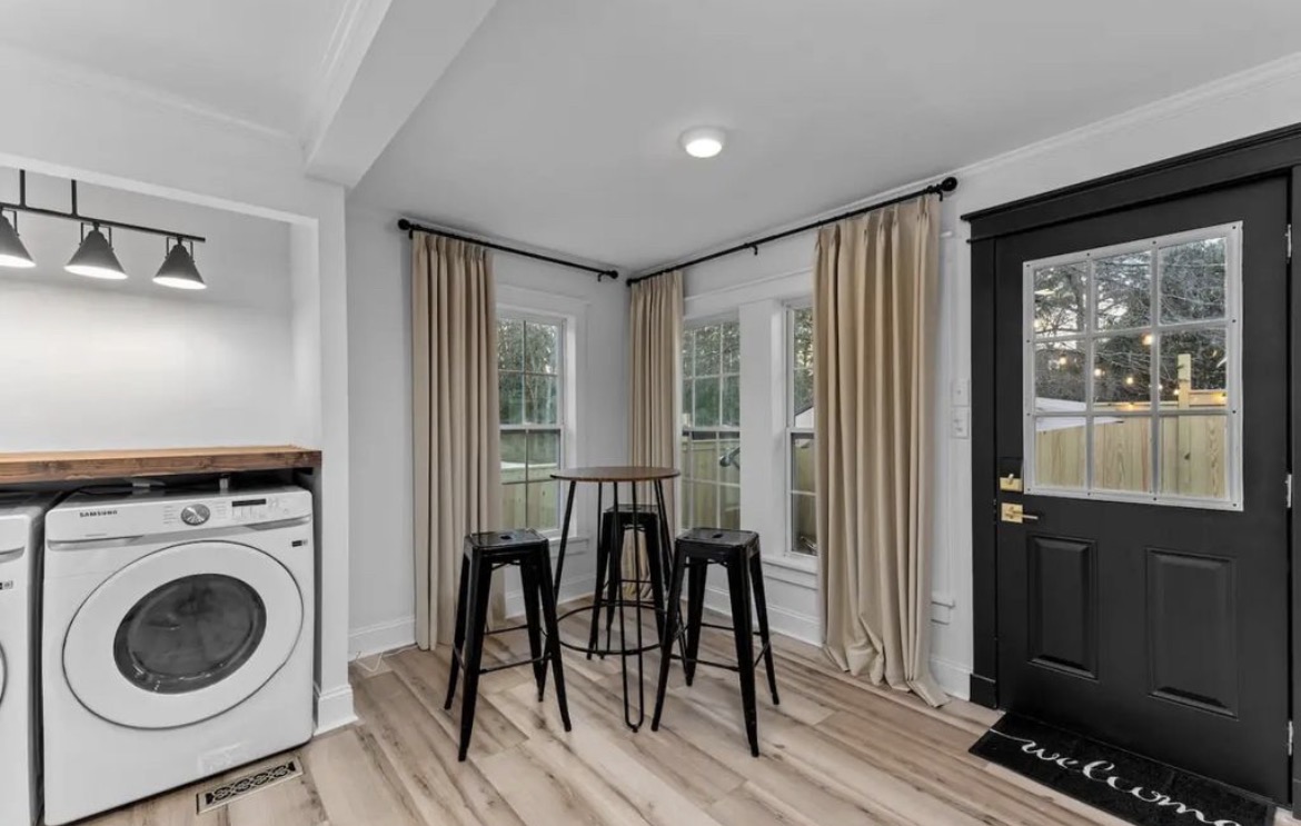 Entry area with black front door, high-top table with stools and laundry nook