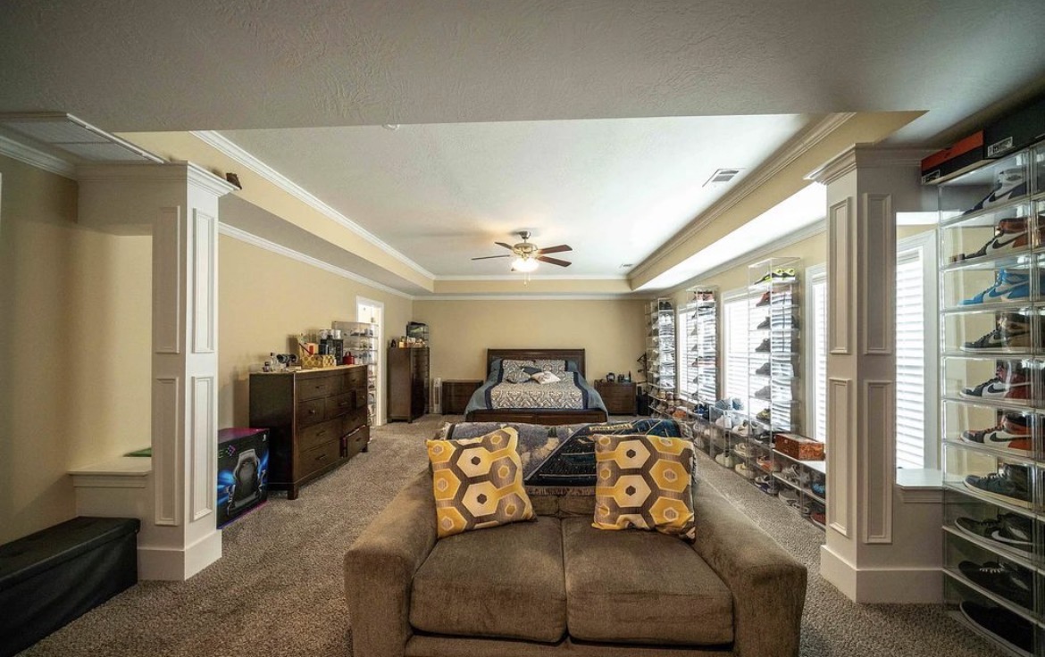 Oversized primary bedroom with king bed, tray ceiling, ceiling fan and sitting sofa