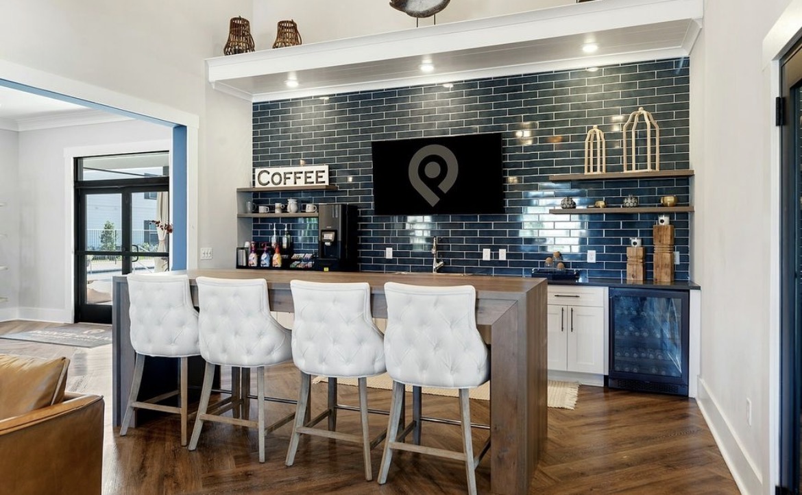Community coffee bar with tufted stools and navy tile wall