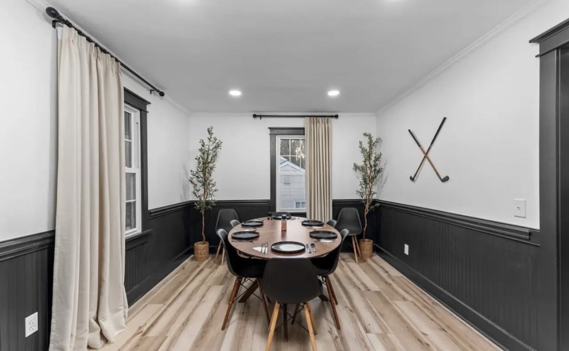 Dining room with oval wood table for six, black wainscoting and crossed golf clubs on the wall