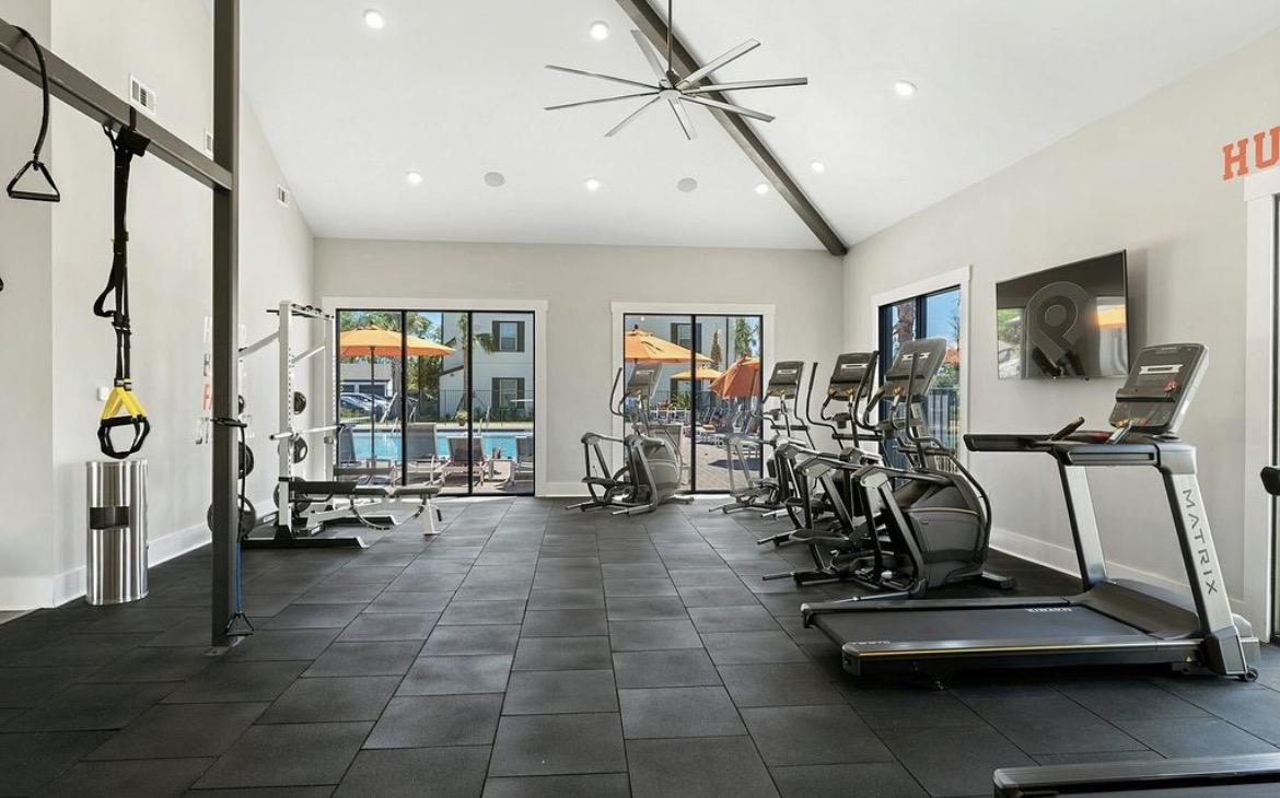Fitness center with treadmills, ellipticals and weight rack overlooking the pool