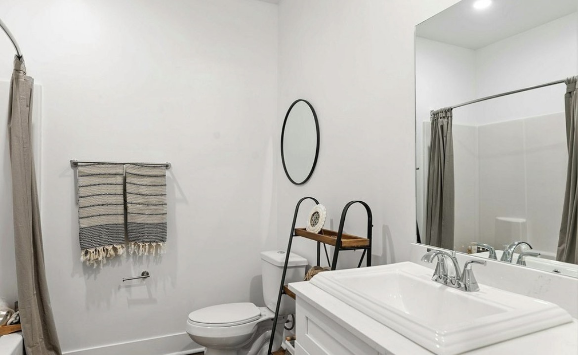 Second bathroom with shower-tub combo, striped towels and large mirror