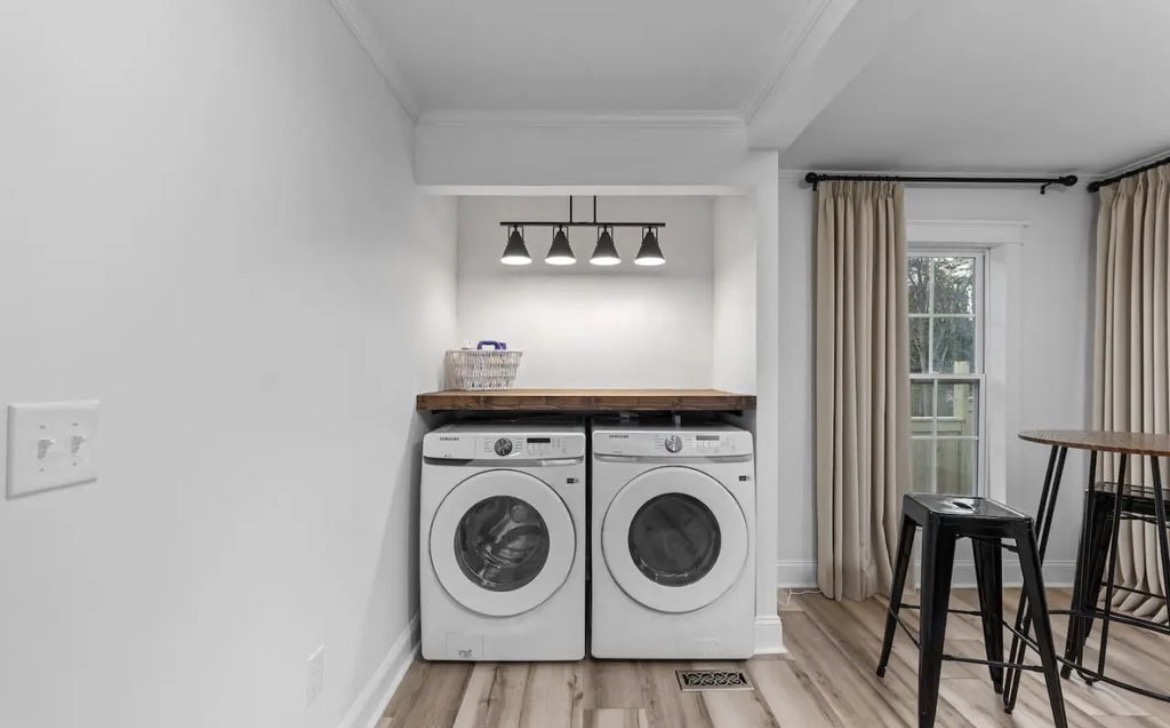 Full-size washer and dryer with butcher block counter under black track lighting
