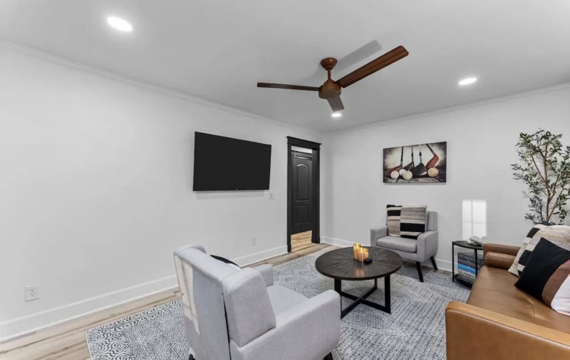Second lounge with wall-mounted TV, armchairs and golf club artwork